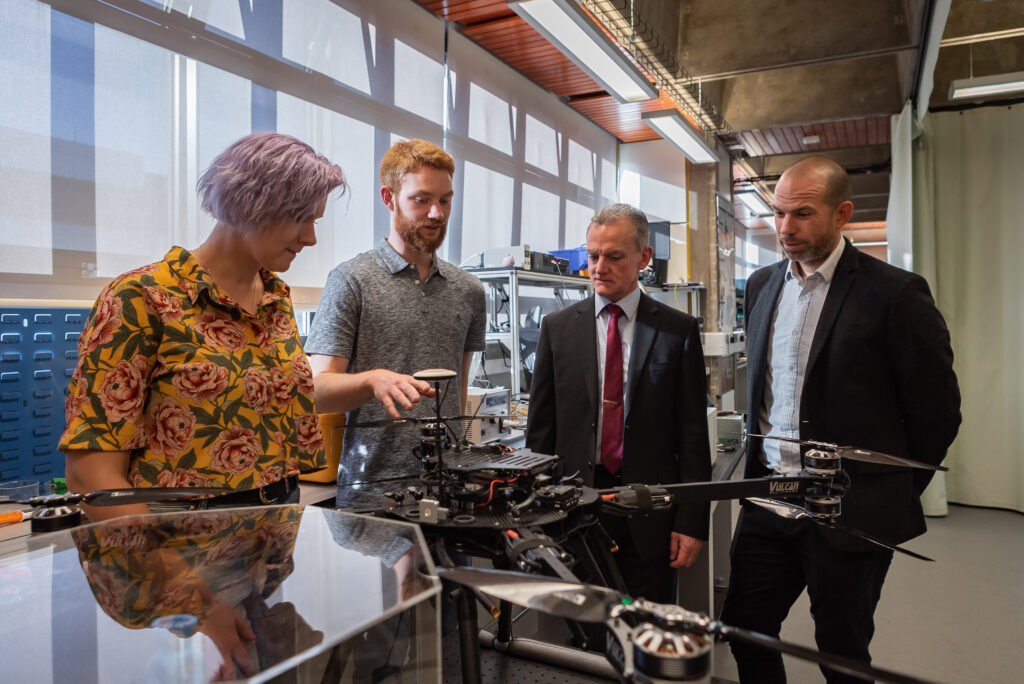 Researchers and visitors in Hub lab looking at sensor