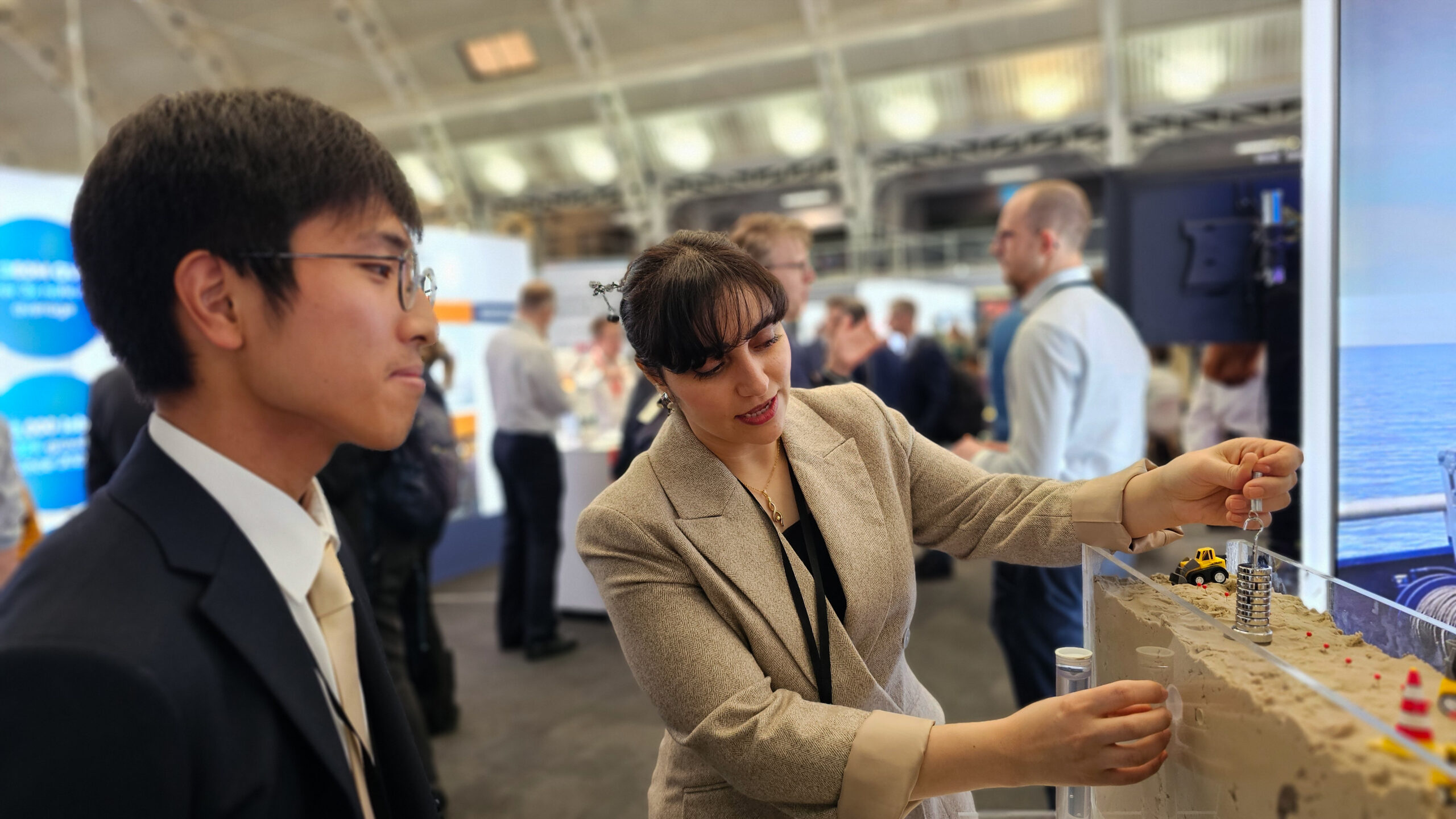 A man observers a woman explaining a technology demo at a conference